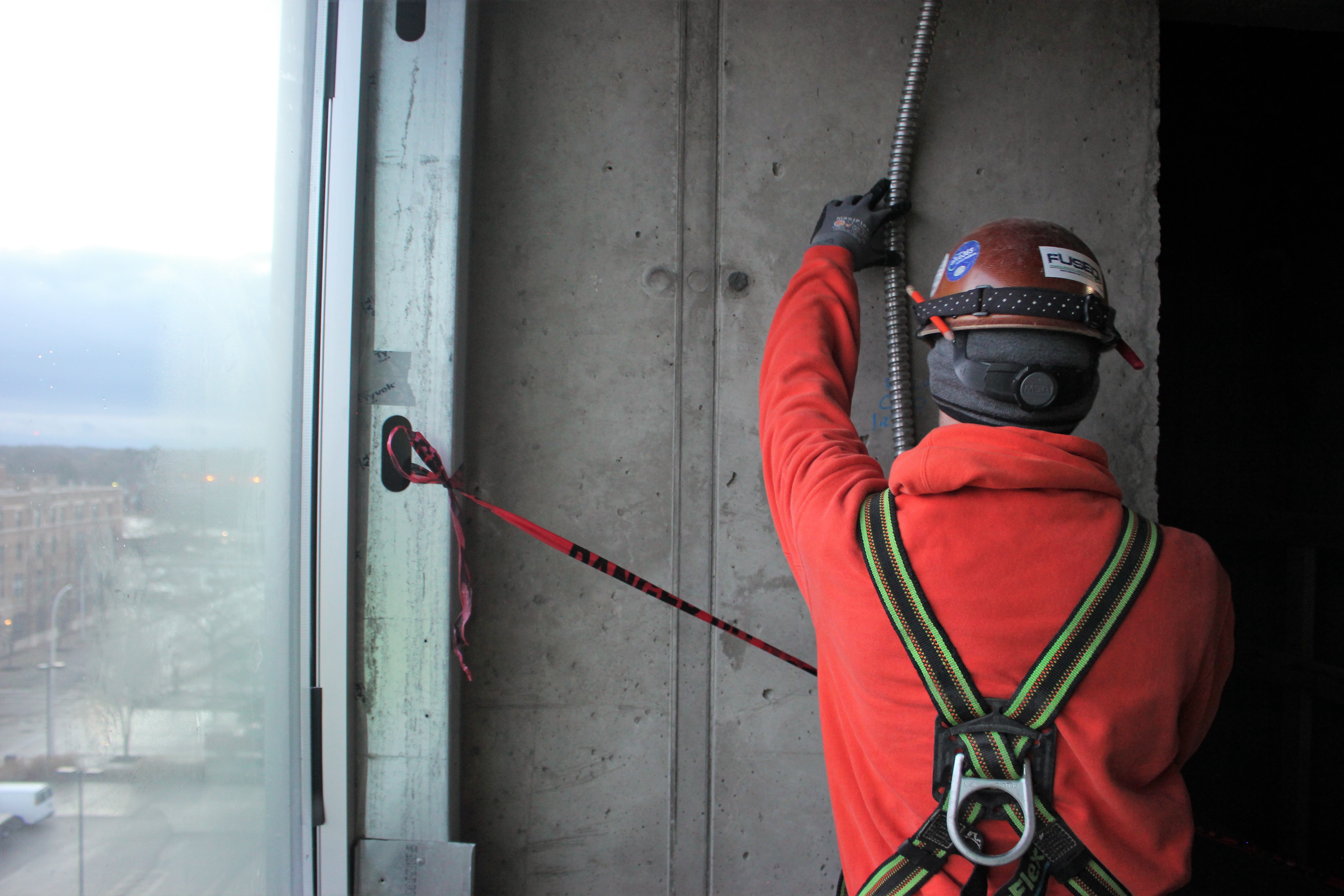 Allied Electric worker in safety gear working on high-rise construction project